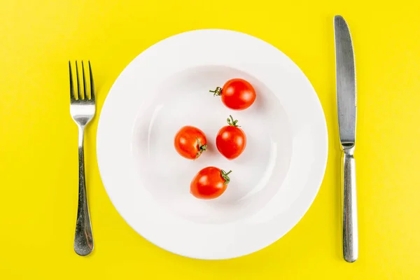 Tomates Uma Placa Branca Com Faca Garfo Fundo Yallow Conceito — Fotografia de Stock