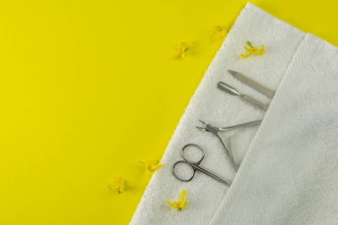 Manikür ve pedikür için kozmetik aletler. Manikür makası, tırnak derisi, beyaz havludaki testereler yalak arka planda duruyor. Açık alanlı en üstteki görünüm.