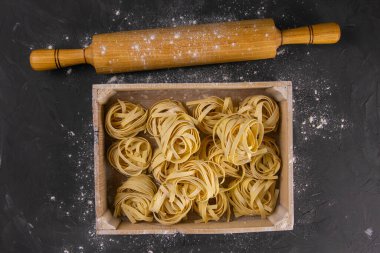 Kırsal ahşap arka planda makarna hazırlamakla geçen bir hayat. Tahta bir kutuda çiğ tagliatelle hamuru ve yumurtası için merdane. Üst Görünüm.