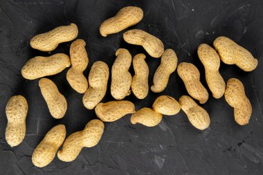 Karanlık bir arka planda yer fıstığı. Kabuklu fıstıklar. Sağlıklı yiyecekler. üst görünüm, yakın plan.