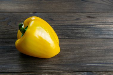 Tek olgun organik tatlı sarı biber. Koyu ahşap masada. Kalp için sağlıklı yiyecek seçimi, yaşam konsepti, kopyalama alanı.
