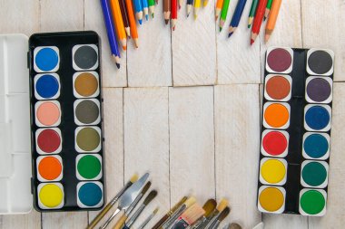 Sanatçı aksesuar koleksiyonu. Çadır bezi, bir tüp yağ boyası, sanat fırçaları, ahşap masada duran palet bıçağı. Sanatçı atölyesi arka planı.