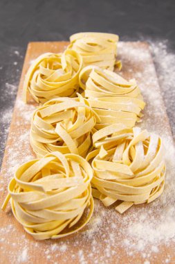 İtalyan ev yapımı çiğ makarna spagettisi ve ahşap tahtada unlu tagliatelle. Düz yatıyordu.