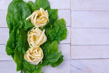 Beyaz ahşap arka planda ıspanak ve makarna, fotoğraf stüdyosu. Açık alanlı en üstteki görünüm.