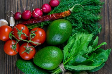 Sağlıklı meyve, fındık ve sebzelerin geçmişi. Avokado, sarımsak, ceviz, vişneli domates, soğan, salatalık, dereotu ve turp. Üst görünüm, yakın plan.