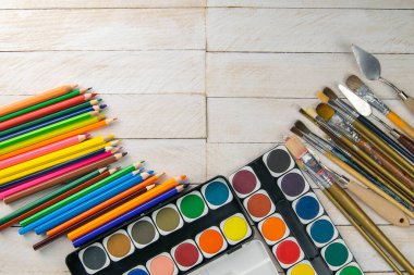Sanatçı aksesuar koleksiyonu. Çadır bezi, bir tüp yağ boyası, sanat fırçaları, ahşap masada duran palet bıçağı. Sanatçı atölyesi arka planı.