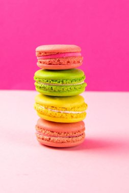 Çok renkli badem kurabiyeleri pembe bir masanın üzerinde duruyor. Yakın plan.