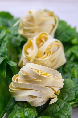 Beyaz ahşap arka planda ıspanak ve makarna, fotoğraf stüdyosu. Üst görünüm, yakın plan.