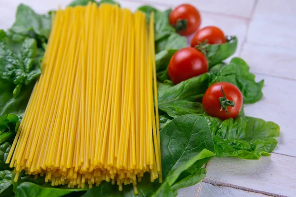 Des Spaghettis Crus Aux Tomates Dressent Sur Des Feuilles Épinards — Photo