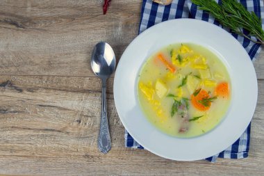 Mantarlı, havuçlu ve peynirli patates kremalı çorba. Üst Manzara. Tabak kareli havlunun üzerinde duruyor, kaşığın yanında..