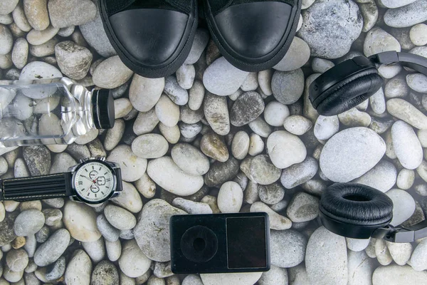 Sneakers, headphones, ipod and clock on a sea stone background. Top views.