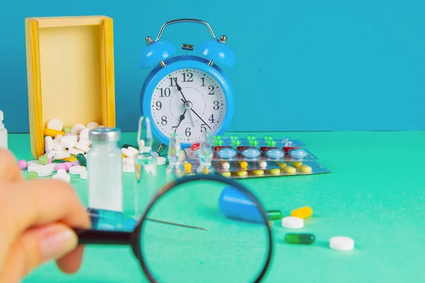 Pharmaceutical research and clinical trials concept. Medicine vial bottle for injection with vaccine and new pharmacy drug in pills and syringe under magnifying glass.