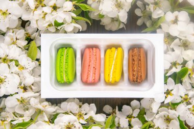 Çiçekli bir elma ağacının bahar dalları beyaz çiçekler ve kırsal ahşap arka planda badem kurabiyeleri, yakın plan..