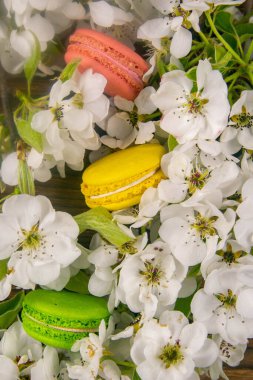 Çiçekli bir elma ağacının bahar dalları beyaz çiçekler ve kırsal ahşap arka planda badem kurabiyeleri, yakın plan..