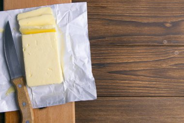 Tahta masanın üzerinde açılmamış bir parça tereyağı. Üst görünüm, yakın plan.