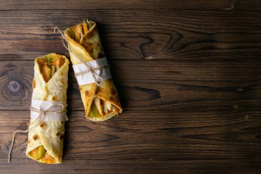 İki adet kebap, et, sebze ve patates kızartması. Tahta bir masada yakın plan Pita ekmeği. Açık alanlı en üstteki görünüm.