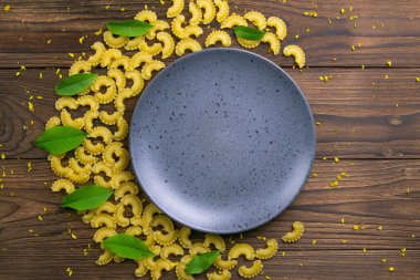 Pene Lisce makarnası, koyu ahşap arka planda gri bir tabağın etrafında bir ay şeklinde. Üst Görünüm.