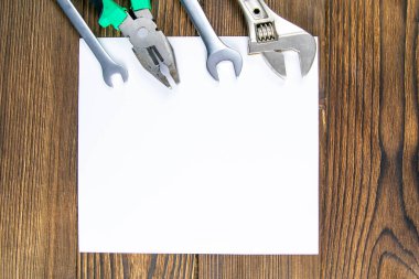 Aletler. Ahşap bir arka planda beyaz bir kağıt üzerinde araba anahtarları. Düz yat. Üst görünüm.