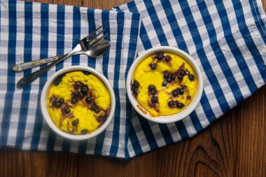 Ahşap bir masada beyaz tabakta çikolatalı ve yaban mersinli süzme peynir güveci. Üst görünüm, yakın plan.