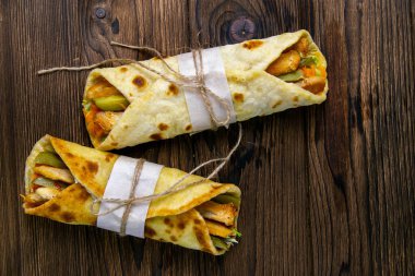 İki döner kebap, et, sebze ve patates kızartması. Pita ekmeği, ahşap bir masada yakın plan..