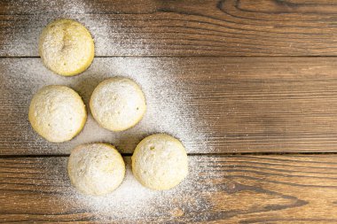 Koyu ahşap masada limonlu kekler. Açık alanlı en üstteki görünüm.