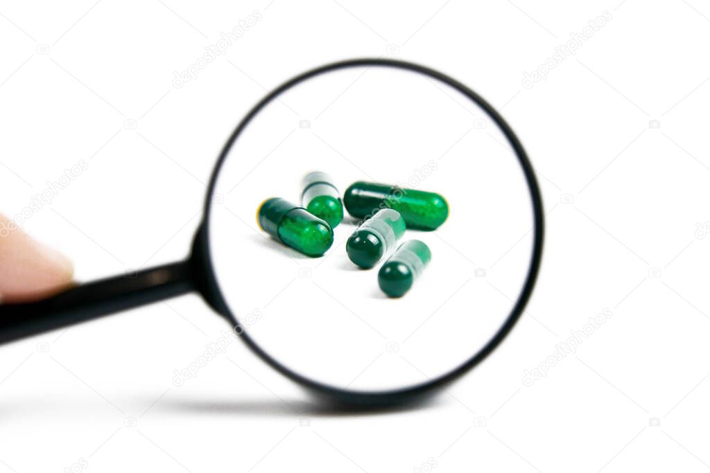 Zooming pills using magnifier glass. Special unique pills isolated on white background.