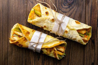 İki döner kebap, et, sebze ve patates kızartması. Pita ekmeği, ahşap bir masada yakın plan..