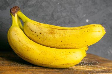 Eski ahşap tahtalarda üç muz yatar. Yakın plan..