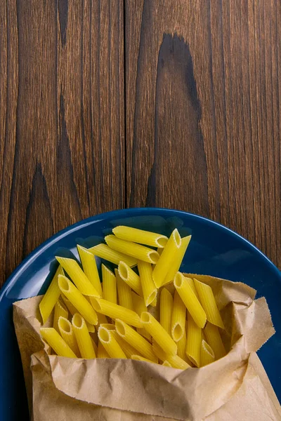 Pene Lisce Pasta Craft Paper Bag Blue Plate Wooden Table — Stock Photo, Image