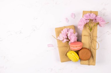 Gri mermer masa üzerinde şakayık ve hediye kutusu olan çok renkli badem kurabiyeleri. Açık alanlı en üstteki görünüm.