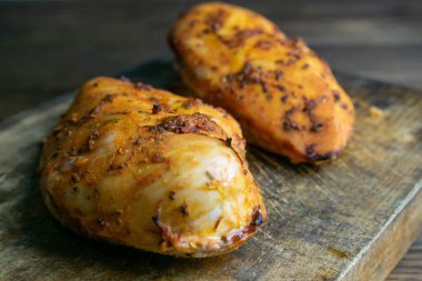 Baharatlı tavuk göğsü ahşap masada tahta kesme tahtasının üzerinde. Üst görünüm, yakın plan.