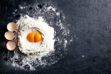Granit mutfak tezgahında buğday unu ve yumurta sarısı yığını. Açık alanlı en üstteki görünüm.