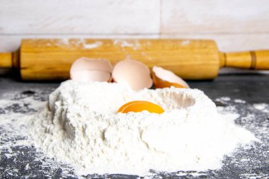 Pişirmek için gerekli malzemeler - hamur, un, merdane, yumurta sarısı ve koyu arkaplanda. Üst görünüm, yakın plan.