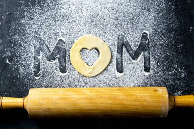 Mather Günü Konsepti. Koyu arkaplanda un ve hamurdan yapılmış bir kelime. Üst görünüm, yakın plan.