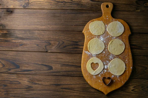 Kalp şeklinde hamur köfteleri, ahşap arka planda un. Hamur köftesi pişiriyorum. Açık alanlı en üstteki görünüm.