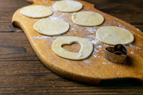 Kalp şeklinde hamur köfteleri, ahşap arka planda un. Hamur köftesi pişiriyorum. Ön manzara, yakın plan..