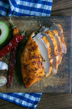 Baharatlı fırında tavuk göğsü, biberiye, avokado ve ahşap masa üzerinde sarımsak. Üst görünüm, yakın plan.