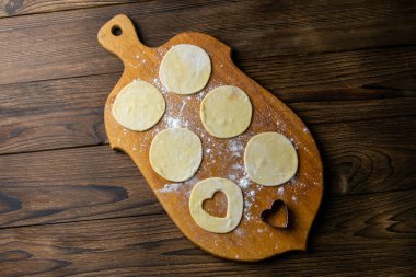 Kalp şeklinde hamur köfteleri, ahşap arka planda un. Hamur köftesi pişiriyorum. Ön manzara, yakın plan..