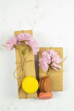 Gri mermer masa üzerinde şakayık ve hediye kutusu olan çok renkli badem kurabiyeleri. Üst görünüm, yakın plan.