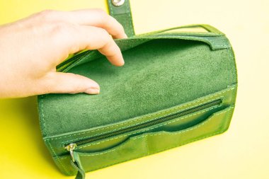 Cüzdanı boş, cüzdanı sarı arka planda bir kadının elinde. Yoksulluk ve mali kriz kavramı.