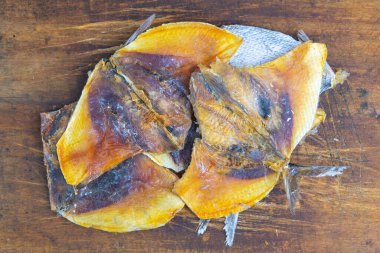 Ahşap arka planda kurutulmuş kelebek şeklinde çipura. Atıştırmalık balıktan biraya. Kapat..