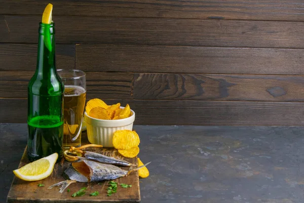 ダークウッドボード上のビール レモンとポテトチップスとフォーム蝶で干し鯛 ビールで魚をつまみなさい 明確な空間で正面の景色 — ストック写真