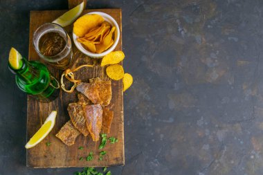 Biberli kurutulmuş morina, limon ve patates cipsi. Balığı birayla atıştır. Açık alanlı en üstteki görünüm.