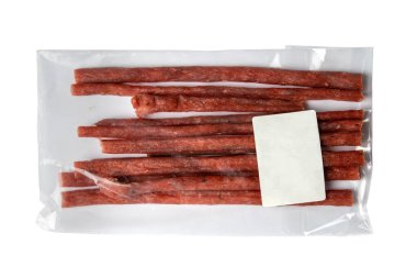 Beyaz arka planda beyaz etiketli şeffaf bir pakette kuru somon çubukları. Atıştırmalık balıktan biraya. Kapat..