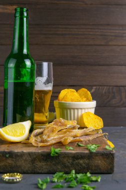 Kurutulmuş ton balığı filetosu, bira, limon ve patates cipsi. Balığı birayla atıştır. Ön manzara, yakın plan..
