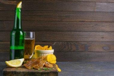 Kurutulmuş yayın balığı filetosu, bira, limon ve patates cipsi. Balığı birayla atıştır. Açık alana sahip ön görünüm.