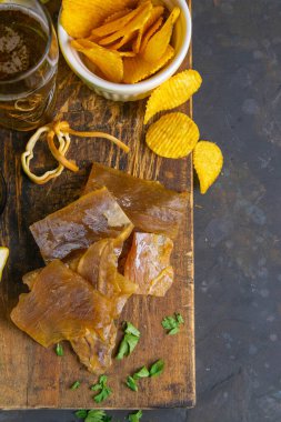 Kurutulmuş yayın balığı filetosu, bira, limon ve patates cipsi. Balığı birayla atıştır. Üst görünüm, yakın plan.