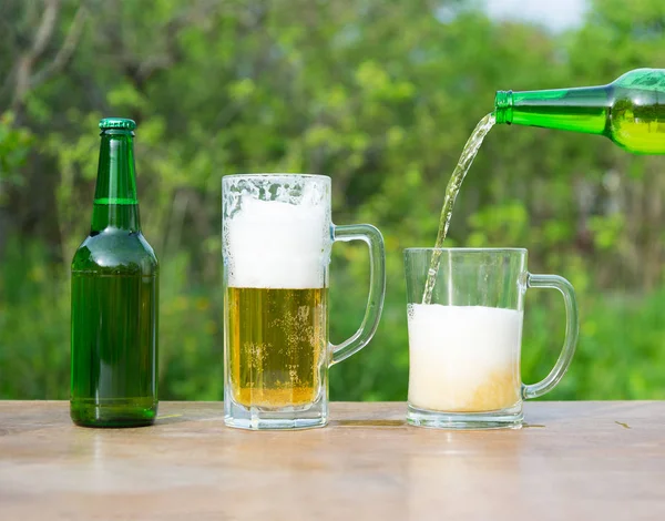 Pouring beer glasses from bottle on green background