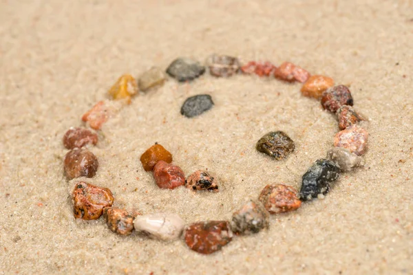 Галечные улыбающиеся лица на песке селективного фокуса — стоковое фото