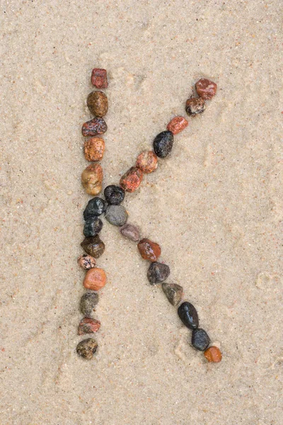 Pebble k letter  on sand — Stock Photo, Image